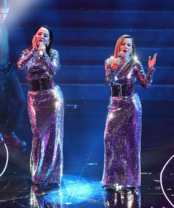 <p>Vestite uguali in lunghi abiti tempestati di paillettes e strizzate in vita da una cintura alta in metallo, le sorelle Iezzi fanno <em>Furore</em> sul palco dell&rsquo;Ariston con un pezzo dance. Il look si ispira a un modello vintage di Dolce & Gabbana, portato in passerella da Gisele B&uuml;ndchen una quindicina d&rsquo;anni fa. L&rsquo;effetto &egrave; stroboscopico.</p>
