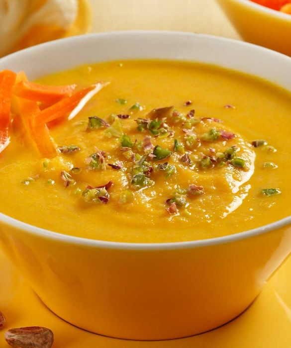 Colorata e delicata, la crema di carote e cavolfiore ai pistacchi è un'idea semplice e gustosa, perfetta per le serate d'autunno. Per prepararla iniziate privando un cavolfiore delle foglie esterne e del torsolo e dividendolo man mano in cimette, poi lavatelo bene sotto l’acqua corrente. Raschiate 300 g di carote e tagliatele a pezzi regolari. Pulite un cipollotto, tritatelo finemente e rosolatelo a fuoco dolce in una casseruola con 4 cucchiai di olio EVO per circa 2 minuti, mescolando spesso. Unite le verdure preparate e proseguite la rosolatura per altri 2 minuti. A questo punto aggiungete nella casseruola 8 dl di brodo vegetale caldo, salate e proseguite la cottura per 20-25 minuti, quindi frullate il composto fino a ottenere una crema. Trasferitela nella casseruola, unite 1 dl di panna fresca, regolate di sale e fate cuocere per circa 2 minuti. Versate la crema nei piatti fondi, completate con 50 g di pistacchi tritati e servite.