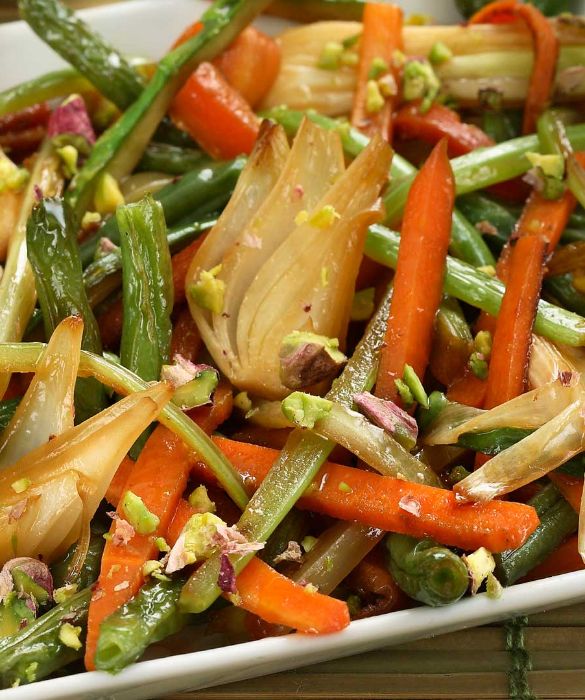 Infine, per i vegetariani e vegani, Verdure saltate con salsa di soia e pistacchi. Per iniziare pulite 250 g di asparagi sottili, raschiate 2 carote, private 2 coste di sedano dei filamenti e tagliate il tutto a bastoncini. Private 100 g di fagiolini dell’eventuale filo e tagliateli a pezzetti. Fate tostare 50 g di granella di pistacchi in un padellino antiaderente per circa un minuto, sempre mescolando, in modo che diventino leggermente dorati. Pulite 3 cipollotti, eliminando parzialmente la parte verde e la radice, e tagliateli in quarti, poi fateli rosolare a fuoco vivace per un minuto in un tegame antiaderente, o in un wok, con 4 cucchiai di olio d'oliva extravergine, mescolando. Unite le verdure precedentemente preparate e cuocete per 5 minuti a fuoco vivace, mescolando. Aggiungete 4 cucchiai di salsa di soia e continuate la cottura per un minuto. Completate con i pistacchi tostati e servite.