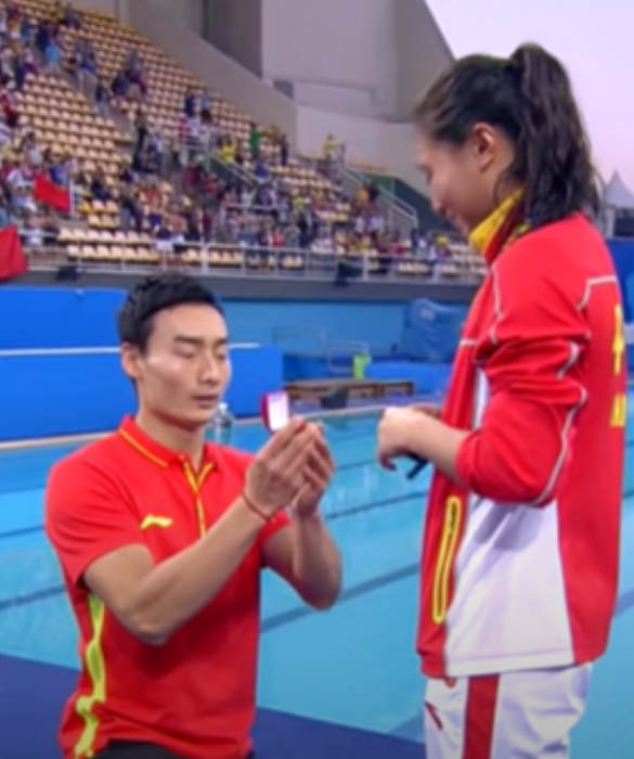 <p>Facciamo un salto temporale di 5 anni: siamo alle Olimpiadi del 2016 di Rio e l&rsquo;atleta cinese He Zi vince la finale di trampolino da 3 metri, mentre Tania Cagnotto si aggiudica l&rsquo;argento. Il tuffatore Qin Kai festeggia insieme a lei inginocchiandosi e chiedendole di sposarlo con tanto di anello.</p>
